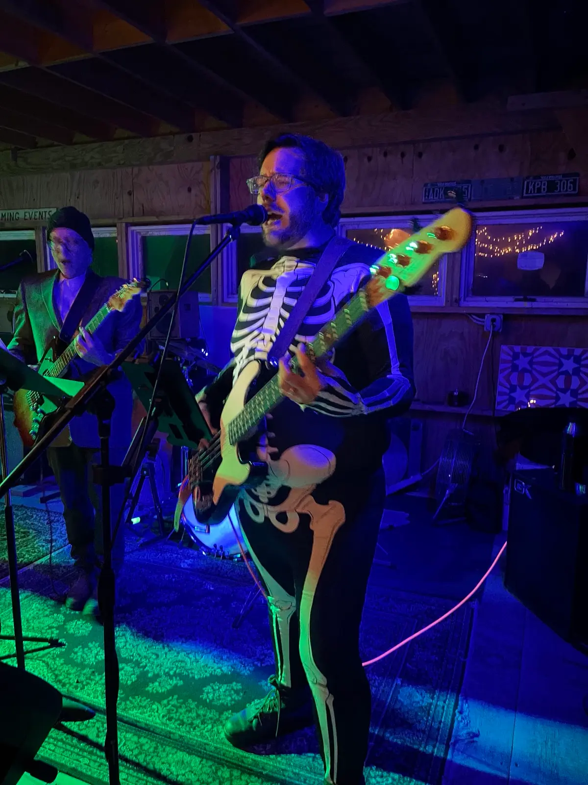 Tom singing into a microphone and playing bass, wearing a skeleton costume